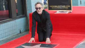 epa11582998 Tim Burton kneels next to his star during a ceremony as he is honored with a star on the Hollywood Walk of Fame in Los Angeles, California, USA, 03 September  2024. The star is in the category of Motion Pictures.  EPA/NINA PROMMER