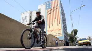 epa13055972 An Iranian man rides his bicycle past an anti-US mural in a street in Tehran, Iran, 22 June 2026. Leaders of the Iranian negotiation team, Mohammad Bagher Ghalibaf and Abbas Araghchi, left the Lucerne Summit in Switzerland after 18 hours of talks with the US, Pakistan, and Qatar.  EPA/ABEDIN TAHERKENAREH RESTRICTIONS: NO Access Israel Media/Persian Language TV Stations Outside Iran/Strictly No Access BBC Persian/VOA Persian/Manoto TV/Iran International TV. (As mandated by Iran's Directorate General for Foreign Media) --
