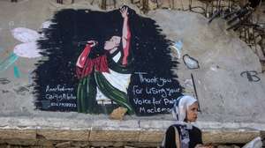 epa13249856 A woman stands in front of a mural by Palestinian artists depicting US rapper Macklemore on the ruins of homes in Gaza City, 19 September 2026. Macklemore was touring as a support act on Ed Sheeran's current Loop Tour but dropped from the tour on 14 September due to the rapper's pro-Palestinian comments.  EPA/MOHAMMED SABER