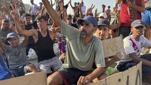 epa13176335 Migrants hold signs and raise their hands during a hunger strike at the El Trampolin beach campsite in Ceuta, Spain, 17 August 2026. The migrants entered the Spanish enclave from Morocco during the mass border crossings that began on 30 July.  EPA/LAURA RINCON