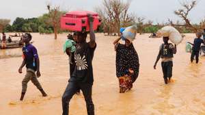 epa11561770 Local residents carry goods as they wade through floodwater during floods in Niamey, Niger, 23 August 2024. In less than three months, floods have caused 217 deaths and 200 injuries in the desert country, and more than 350,000 people were affected, according to the military authorities. The flooding of rivers in Niger is due to the heavy rains that have been falling on the Sahel region since June.  EPA/ISSIFOU DJIBO