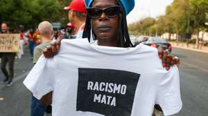 Uma manifestante mostra uma camisola onde se lê "racismo mata"