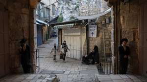 epa12790254 Palestinians pass by a Ultra Orthodox Jewish men praying next to a closed gate leading to Al Aqsa mosque compound in Jerusalem's old city, on 02 March 2026. Due to the home front instructions following Iran's retaliatory airstrikes, Israeli police ordered the closure of the doors of the Church of the Holy Sepulchre, the Western Wall, and the Al Aqsa mosque compound in the Old City of Jerusalem.  EPA/ATEF SAFADI