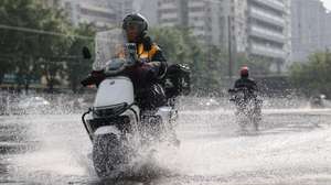 epa13162651 A person rides a scooter in the rain in Beijing, China, 12 August 2026. Beijing activated a Level II flood-control emergency response on 11 August. According to the Beijing Meteorological Observatory, heavy rain is expected from 11 to 13 August.  EPA/WU HAO