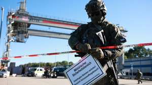 epa13262846 A Military Police officer with a rifle installs a warning sign for a military security area during a staged drone attack incident at a freight yard of German railways Deutsche Bahn during the military exercise 'Red Storm Charlie' in Hamburg, Germany, 25 September 2026. Around 500 officers from the German Armed Forces (Bundeswehr) and civilian emergency services took part in a joint defence exercise aimed at practising civil defence protocols and crisis response.  EPA/CLEMENS BILAN