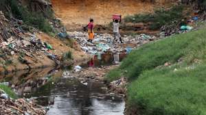 Habitantes atravessam uma enorme vala onde se acumulam detritos e águas paradas no Bairro Paraíso, conhecido pelos níveis elevados de pobreza e criminalidade, a doença e a morte vieram afligir ainda mais os moradores, em Luanda, 09 de janeiro de 2025. Pelo menos cinco pessoas foram oficialmente proclamadas vítimas de cólera, doença ligada à contaminação fecal associada à falta de saneamento e tratamento de água e má higiene, e os habitantes estão preocupados pedindo a intervenção das autoridades angolanas. (ACOMPANHA TEXTO DA LUSA DO DIA 12 DE JANEIRO DE 2025). AMPE ROGÉRIO/LUSA