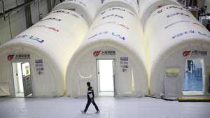 epa08743677 A man walks by a cluster of inflatable, movable laboratories equipped with a medical waste exhaust system and COVID-19 nucleic acid detection instruments in Qingdao in east China's Shandong province, China, 14 October 2020. The pop-up labs, known as Huo-Yan Laboratories, will facilitate the city's ambition to test its nine million citizens in five days.  EPA/ZHANG JINGANG CHINA OUT