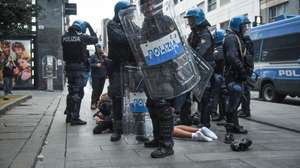 epa13314005 Italian police officers in riot gear stand around a person lying on the pavement during unrest near Piazza del Duomo in Milan, Italy, 18 October 2026. Clashes between protesters and police broke out during a demonstration against the rising cost of living on 17 October, followed by further disturbances in the city center on 18 October.  EPA/MATTEO CORNER