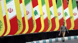 epaselect epa11672953 An Iranian man walks past a decoration of Iranian-Lebanese and Hezbollah flags in a street in Tehran, Iran, 21 October 2024. Iranian supreme leader Ayatollah Ali Khamenei on 19 October issued a message over the death of Yahya Sinwar, stating that 'the resistance did not stop after the death of its leaders, and it will not stop'. The Israeli Army, Tsahal, on 17 October 2024 confirmed that Hamas leader Yahya Sinwar was 'eliminated' on 16 October 'after a year-long pursuit'.  EPA/ABEDIN TAHERKENAREH