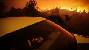 Uma criança aguarda dentro de um carro ao pé dàs chamas que consomem floresta durante um incêndio em Oliveira de Frades, 7 de setembro de 2020. Este incêndio no concelho de Oliveira de Frades, no distrito de Viseu, mobilizou 327 bombeiros, apoiados por 103 viaturas e oito meios aéreos. NUNO ANDRÉ FERREIRA/LUSA