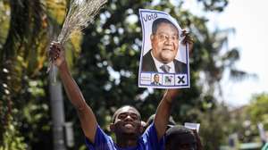 epa11645626 A supporter of the presidential candidate and president of the main opposition party Mozambican National Resistance (RENAMO) Ossufo Momade holds up his election campaign poster during a campaign event in Maputo, Mozambique, 06 October 2024. Mozambique is holding its seventh presidential and legislative elections on 09 October, as well as the fourth elections for provincial assemblies and governors. The current head of state, Filipe Nyusi, has reached the constitutional limit of two terms and is no longer running.  EPA/LUISA NHANTUMBO