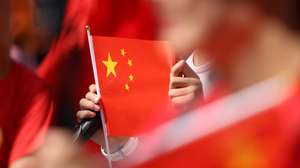 epa13274330 A woman holds a Chinese flag in Hong Kong, China, 01 October, 2026. The city celebrates China's National Day on 01 October 2026, marking the 77th founding anniversary of the People's Republic of China.  EPA/MAY JAMES