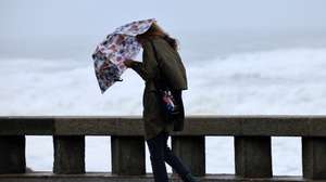 Uma mulher tenta proteger-se da chuva e do vento na marginal da Foz do Douro no Porto, 17 de outubro de 2023. Mais de 40 ocorrências foram registadas desde as 00:00 de hoje, a maioria na Grande Lisboa e em Setúbal, devido ao mau tempo, segundo informação disponível no ‘site’ da Autoridade Nacional de Emergência e Proteção Civil (ANEPC). ESTELA SILVA/LUSA