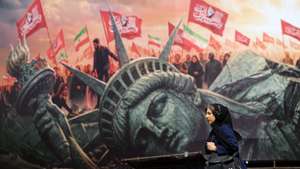 epa13165938 An Iranian woman walks next to an anti-US billboard at the Enghelab square in central Tehran, Iran, 13 August 2026. Tensions between Iran and the US remain high as opposing claims persist over shipping control in the Strait of Hormuz.  EPA/ABEDIN TAHERKENAREH RESTRICTIONS: NO Access Israel Media/Persian Language TV Stations Outside Iran/Strictly No Access BBC Persian/VOA Persian/Manoto TV/Iran International TV. (As mandated by Iran's Directorate General for Foreign Media) --