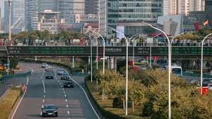 epa13262481 People walk across a pedestrian bridge with screen showing the latest stock exchange and economy data, in Shanghai, China, 25 September 2026.  EPA/ALEX PLAVEVSKI