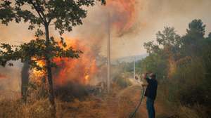 Um popular ajuda no combate a um incêndio na Aldeia de Gontães, Vila Real, 4 de agosto de 2025. Pelas 16:30, mais de 2.200 operacionais e cerca de 710 meios de transporte, inclusive 19 meios aéreos, combatiam 63 incêndios rurais em Portugal continental, com destaque para os fogos em Vila Real e Celorico de Basto (distrito de Braga), segundo a Proteção Civil. PEDRO SARMENTO COSTA/LUSA