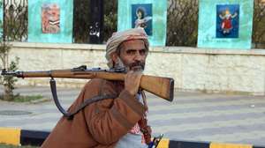 epa12616107 An armed man walks past paintings on display on a fence in Sana'a, Yemen, 28 December 2025. Yemen has been split by over 10 years of conflict, with the Houthis controlling large parts of the north while southern separatists have consolidated their grip in the south.  EPA/YAHYA ARHAB