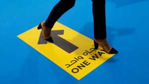 epa09225056 A visitor walks on a one way sign during the 20th edition of Dubai Airport Show, in Dubai, United Arab Emirates, 24 May 2021. Dubai Airport Show 2021 is bringing over 95 exhibitors and more than 100 hosted buyers from across the globe, the event is running until 26 May.  EPA/ALI HAIDER