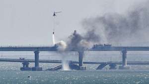epaselect epa10230640 A firefighter helicopter pours water on fire on a collapsed part of the Kerch Strait bridge in Crimea, 08 October 2022. According to Russian authorities, "an explosion was set off at a cargo vehicle on the motorway part of the Crimean bridge on the side of the Taman peninsula, which set fire to seven fuel tanks of a train that was en route to the Crimean peninsula. Two motorway sections of the bridge partially collapsed."  EPA/STRINGER