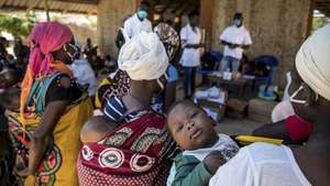 Mães com as suas crianças durante uma consulta de uma brigada móvel do Fundo das Nações Unidas para a Infância (UNICEF), um grupo de profissionais de saúde que viaja de ambulância e vai ao encontro das comunidades mais afastadas em vez de esperar por elas em centros de saúde, Impire, Moçambique, 24 de julho de 2020. Em menos de uma hora, na povoação de Impire, distrito de Metuge, sul de Cabo Delgado, juntam-se dezenas de mães com as suas crianças - a maioria ainda bebés - para a brigada observar, com pesagem, medição de altura, avaliação à subnutrição, seguindo-se uma consulta, vacinação e entrega da medicamentos numa rotina que inclui a observação das mães e decorre desde manhã até o sol se pôr, num pavilhão empoeirado. (ACOMPANHA TEXTO DE 25 DE JULHO DE 2020). RICARDO FRANCO/LUSA