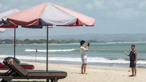 epa09454511 Tourists take photos at a beach in Kuta, Bali, Indonesia, 08 September 2021. The Indonesian government extended the current restrictions on community activities (PPKM) until 13 September 2021 with a number of relaxations for community activities, including reopening schools, public areas and shopping malls, amid the ongoing coronavirus pandemic.  EPA/MADE NAGI