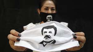 epa08367814 A person holds a face mask, which depicts famed drug lord Joaquin 'El Chapo' Guzmanto, in Guadalajara, Jalisco, Mexico, 16 April 2020. According to media reports, Alejandrina Guzman, daughter of Joaquin 'El Chapo' Guzman, has helped in the distribution of aid and supplies, labelled with the name and image of her father, to members of the public during the outbreak of coronavirus in Mexico.  EPA/Francisco Guasco