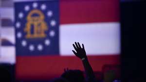 epa10295077 A supporter cheers with the Georgia flag in the background during the election night party for Democrat US Senator Raphael Warnock in Atlanta, Georgia, USA, 08 November 2022. The US midterm elections are held every four years at the midpoint of each presidential term and this year include elections for all 435 seats in the House of Representatives, 35 of the 100 seats in the Senate and 36 of the 50 state governors as well as numerous other local seats and ballot issues.  EPA/JOHN AMIS  EPA-EFE/JOHN AMIS