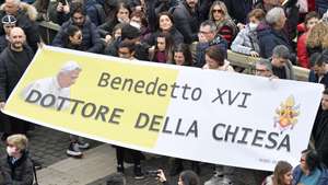 epa10392270 A handout picture provided by the Vatican Media shows faithfuls holding a banner reading 'Benedict XVI - Doctor of the Church' in Saint Peter's Square as Pope Francis leads his Angelus prayer, in Vatican City, 06 January 2023. Pope Emeritus Benedict XVI died on 31 December 2022 at his Vatican residence, at the age 95. His funeral took place on 05 January.  EPA/VATICAN MEDIA HANDOUT  HANDOUT EDITORIAL USE ONLY/NO SALES