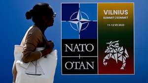 epaselect epa10735912 A woman passes by a NATO poster at the NATO summit venue in Vilnius, Lithuania, 09 July 2023. NATO Summit will take place in Vilnius on 11 and 12 July 2023.  EPA/FILIP SINGER