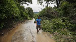 epa11430993 A man walks along a path flooded due to heavy rains in Soyapango, El Salvador, 21 June 2024 (issued 22 June 2024). A Salvadoran family spent the night in a boat after the collapse of an earthen dam destroyed their home and heavy rains threatened more landslides, adding to the more than 3,800 people who have had to be evacuated because of the rains that have lashed El Salvador since last week and have left at least 19 people dead and two missing.  EPA/Rodrigo Sura