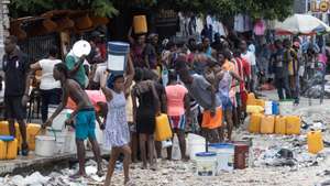 epa11389986 Citizens walk with containers for water collection in Port-au-Prince, Haiti, 04 June 2024. Amnesty International (AI) expressed on 04 June its concern over the &#039;lack of transparency&#039; in relation to the establishment of human rights safeguards for the Multinational Security Support Mission (MSS) in Haiti, expected to deploy in the coming weeks, and calls for these to be respected.  EPA/ORLANDO BARRIA