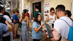 Turistas fazem vila para provar bebidas típicas num bar no centro histórico de Sintra, 16 de agosto de 2024. A Associação QSintra - Em Defesa de um Sítio Único - lançou uma iniciativa com faixas nas janelas e varandas e cartazes nas montras de lojas, restaurantes e cafés, exigindo à Câmara Municipal de Sintra medidas contra o "turismo de massas e caos no trânsito", com o objetivo de que a cidade não se transforme "num mero parque de diversões congestionado", pondo em causa o seu caráter de "sítio único". (ACOMPANHA TEXTO DA LUSA DO DIA 20 DE AGOSTO DE 2024). ANTÓNIO PEDRO SANTOS/LUSA