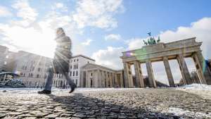 epa09004185 A woman walks on the deserted Pariser Platz square in front of the Brandenburg Gate in Berlin, Germany, 11 February 2021. On 10 January 2021, German Chancellor Angela Merkel and the regional head of states, decided a prolongation of the coronavirus caused lockdown until 07 March 2021.  EPA/CLEMENS BILAN