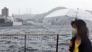 epa11493719 A woman walks in a harbour as Typhoon Gaemi is set to make landfall, in Keelung, Taiwan, 24 July 2024. After having hovered in the waters of the Philippines, Typhoon Gaemi is expected to make landfall in Taiwan on the evening of 24 July, with the Taiwanese weather agency issuing sea and land warnings. People are also reminded to monitor changes to international and domestic flights as disruptions may occur due to the tropical storm that brings in heavy rain and powerful winds.  EPA/DANIEL CENG