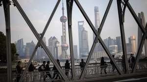 epa11732898 People walk along a bridge with high-rise buildings seen in the background, in the Bund district of Shanghai, China, 21 November 2024.  EPA/ANDRES MARTINEZ CASARES
