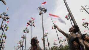 epaselect epa11552479 A participant waves the Indonesia's national flag after a greased pole-race locally known as 'Panjat Pinang' to mark the 79th anniversary of Indonesia's independence day at Ancol Beach in Jakarta, Indonesia, 17 August 2024. Indonesia celebrated its Independence Day with ceremonies held for the first time at Garuda Palace in the new capital of Nusantara in East Kalimantan, as well as at the Presidential Palace in Jakarta, celebrating the 79th anniversary of its independence from the Netherlands on 17 August 1945.  EPA/BAGUS INDAHONO