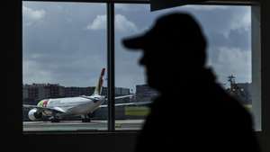 Um agente da Polícia de Segurança Pública observa um avião da TAP, no Aeroporto Humberto Delgado, em Lisboa, 15 de abril de 2025.  JOSÉ SENA GOULÃO/LUSA