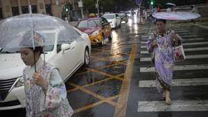 epa12233671 Women wearing traditional dresses carry umbrellas to protect themselves from rain while walking along a street of Beijing, China, 12 July 2025.  EPA/ANDRES MARTINEZ CASARES
