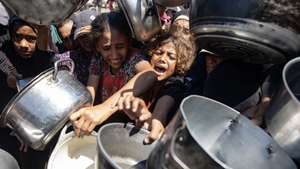 epaselect epa12317917 Palestinians queue to receive a meal from a kitchen that provides free food for displaced people in Khan Yunis, southern Gaza Strip, on 23 August, 2025.  EPA/HAITHAM IMAD
