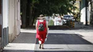 Uma mulher caminha num bairro residencial perto da Praça de Londres, em Lisboa, 14 de agosto de 2025. verão. ANTÓNIO PEDRO SANTOS/LUSA