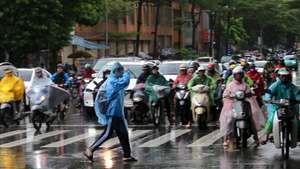 epa12413882 People riding motorbikes wait at a traffic light in the rain in Hanoi, 29 September 2025. Thirteen people were reported dead and several missing as Typhoon Bualoi made landfall in Vietnam, according to state media.  EPA/LUONG THAI LINH