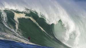 epa09694904 Surfer Jake Kolnik rides a wave at Sunset offshore reef in the Atlantic Ocean outside Cape Town, South Africa, 19 January 2022. Big swells are unusual during the southern hemisphere summer but a storm in the South Atlantic generated powerful swells that broke on the Cape's outer reefs making good conditions for the sport. This is the first big swell of the year. The waves were too big to paddle into so surfers used wave runners to tow each other into the waves.  EPA/NIC BOTHMA