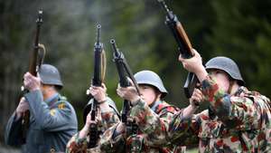 epa09904269 Soldiers of the Swiss Army Honor Troop dressed in contemporary uniforms shoot with rifles outside of the artillery fort of Dailly, T2, one of the largest and most heavily armed forts in Switzerland, in Lavey-Morcles, Switzerland, 23 April 2022. The fortress has opened 1.8 of the almost 20 kilometres-long Swiss army fortress, the largest underground military fortress of Switzerland which is not used by the Swiss army since 1994, to visitors.  EPA/LAURENT GILLIERON