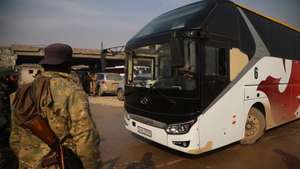 epaselect epa12637785 A soldier stands next to one of the buses waiting to evacuate the Kurdish-led Syrian Democratic Forces (SDF) fighters from Aleppo, northern Syria, 09 January 2026. The Syrian Ministry of Defense announced a ceasefire agreement in the neighborhoods of Sheikh Maqsoud, Ashrafieh, and Bani Zaid of Aleppo allowing the withdrawal of members of the SDF through safe passage to areas in northeastern Syria, after several days of deadly clashes between the Syrian government and the SDF.  EPA/BILAL AL-HAMMOUD