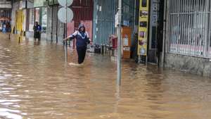 Uma popular caminha por uma rua inundada devido às chuvas na cidade de Maputo, Moçambique, 12 de março de 2026. A cidade de Maputo regista desde a manhã de hoje novas cheias, que condicionam a circulação em várias zonas da capital moçambicana, devido às fortes chuvas, pela segunda vez em menos de uma semana. (ACOMPANHA TEXTO). LINA CEBOLA/LUSA
