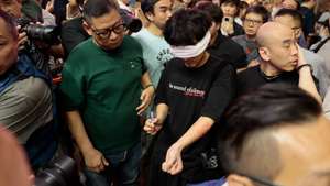 epa13015331 Plain clothes police watch an activist perform near Victoria Park, in Hong Kong, China, 04 June 2026. The park is historically where the now-disbanded Hong Kong Alliance in Support of Patriotic Democratic Movements of China organised annual candlelight vigils since 1990 to mourn the victims of China's 1989 Tiananmen Square crackdown. The vigil, once the only large-scale public commemoration of the crackdown on Chinese soil, has been banned since Beijing imposed a national security law on Hong Kong in 2020.  EPA/MAY JAMES
