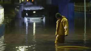epa13118289 A man attempts to move a truck stuck on a flooded street following heavy rains in the San Bernardo district of Santiago, Chile, 17 July 2026.  EPA/ELVIS GONZALEZ
