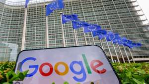epa13128008 A general view shows a Google logo on an iPhone screen in front of the European Commission building in Brussels, Belgium, 23 July 2026. The EU Commission has fined Google 890 million euros for breaching the Digital Markets Act. The Commission made two rulings, finding Google in breach of the DMA for favouring its own services on Google Search and for restricting businesses from directing consumers to cheaper alternative purchase channels on Google Play. The Commission issued Google fines of 460 million and 430 million euros respectively for these breaches.  EPA/OLIVIER MATTHYS