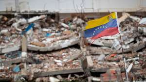 epa13158506 A Venezuelan flag flutters in the wind amid debris in La Guaira, Venezuela, 09 August 2026. La Guaira is the state hardest hit by the two earthquakes that struck Venezuela on 24 June.  EPA/RONALD PENA R