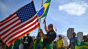 epa12560952 A supporter of former Brazilian President Jair Bolsonaro waves a US flag and a Brazilian flag during a protest against his imprisonment at the Esplanade of the Ministries government complex in Brasilia, Brazil, 30 November 2025.  EPA/ANDRE BORGES